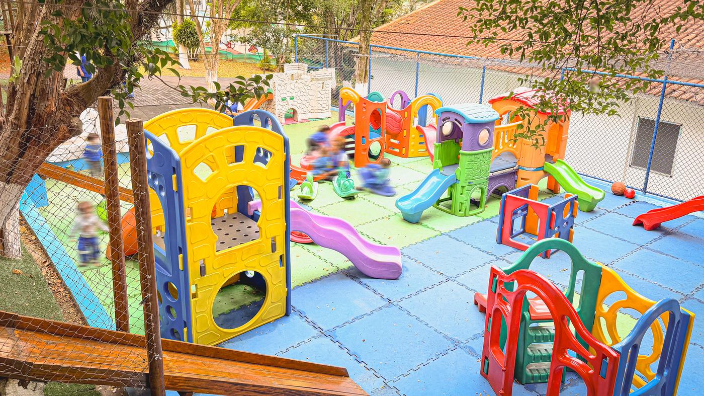 Playground colorido da Escola Crystal em área externa arborizada
